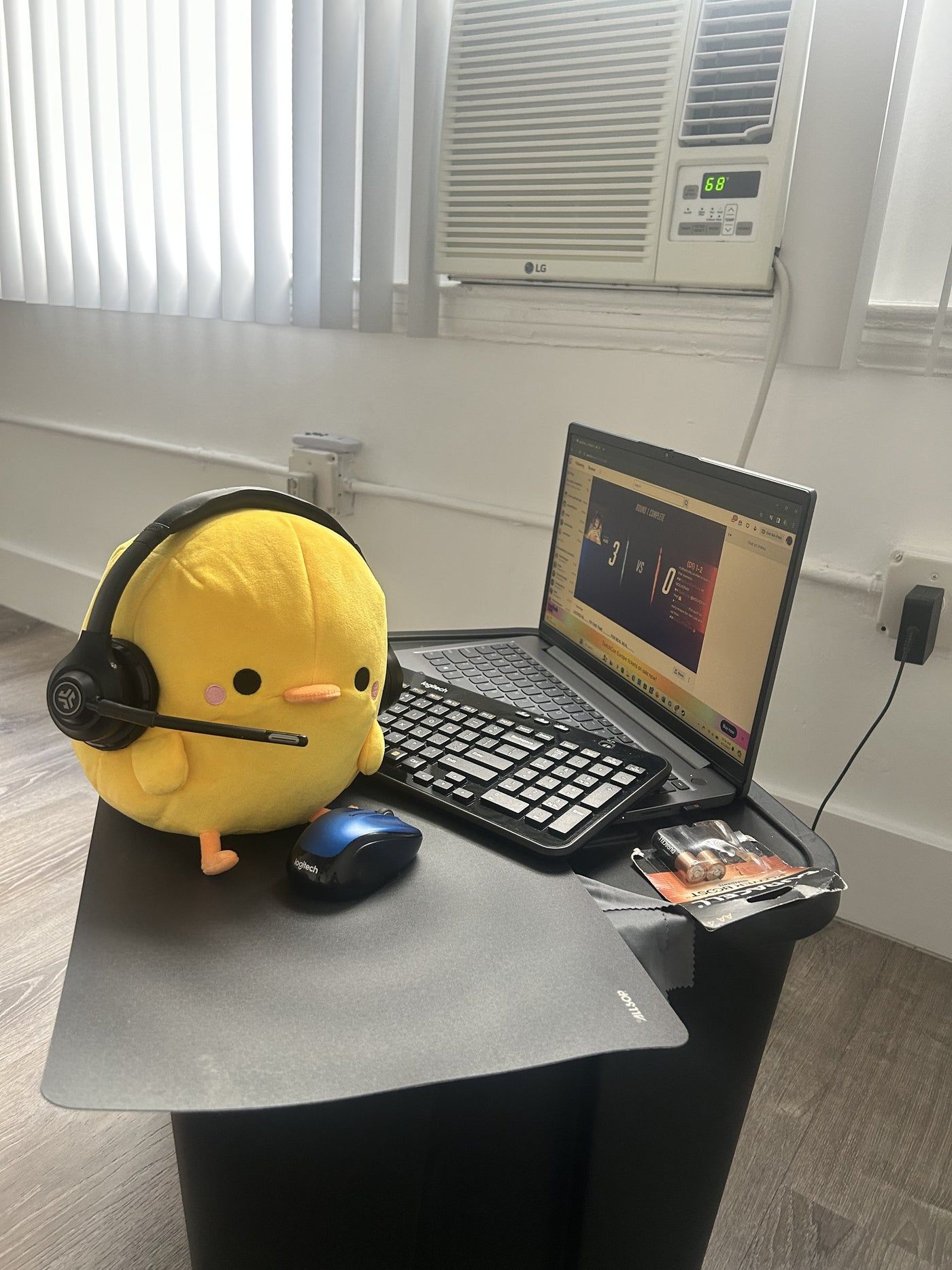 Henry plush wearing headphones at a laptop desk