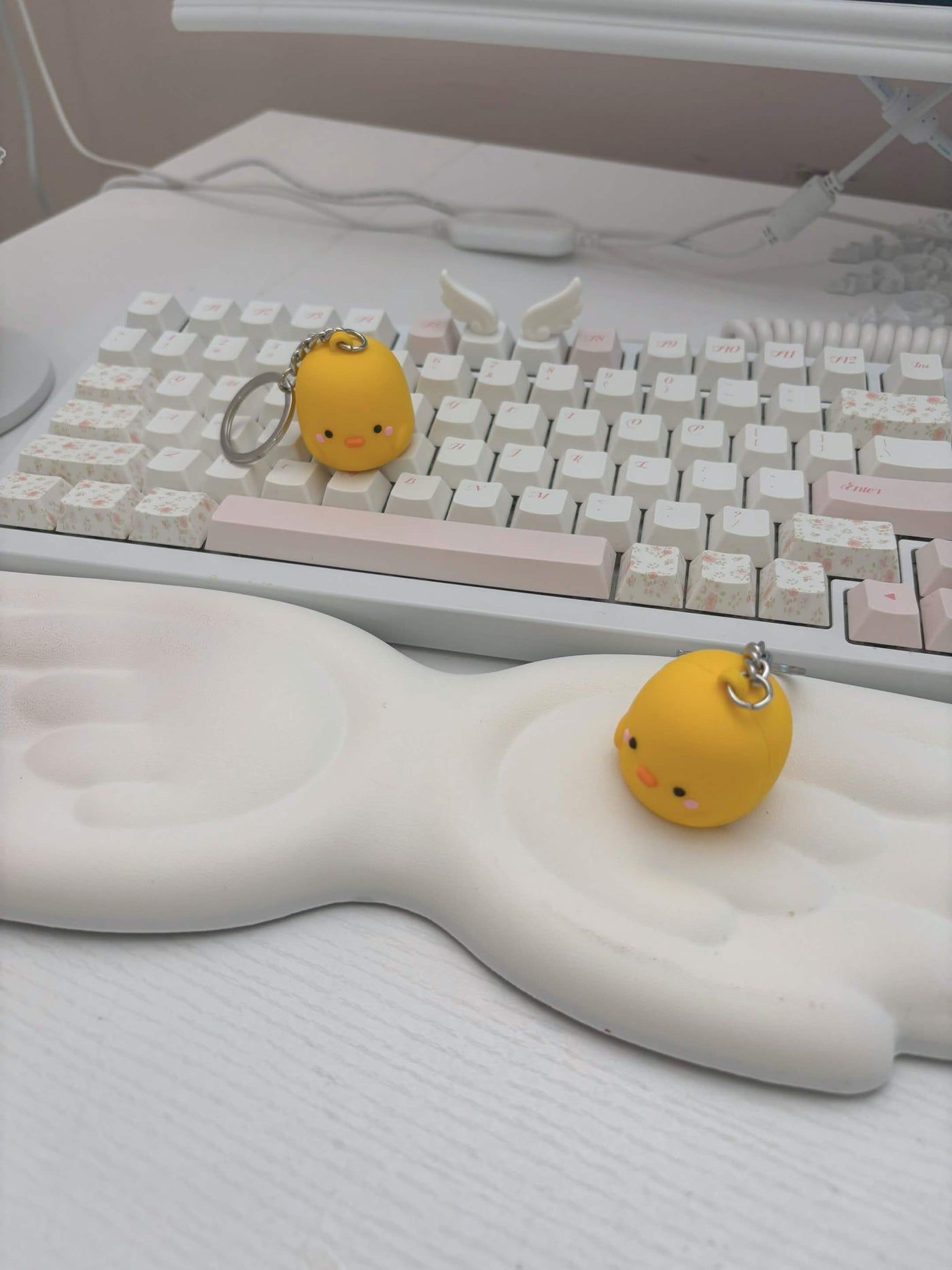 Two yellow Henry keychains resting on a white keyboard