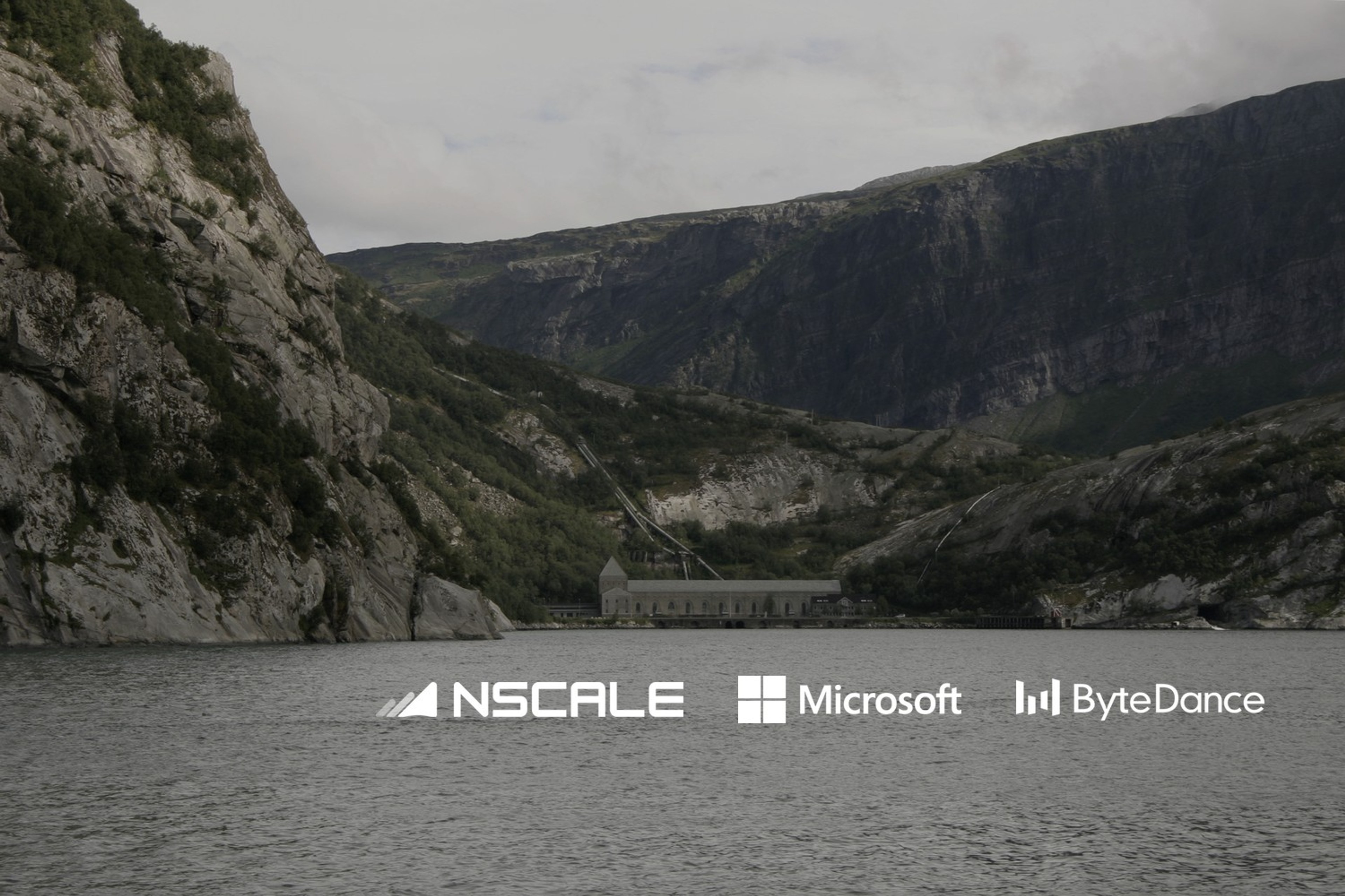 Glomfjord kraftverk sett over vannet, omgitt av bratte fjell i Nordland. Med logoene til Nscale og Microsoft og ByteDance lagt på.