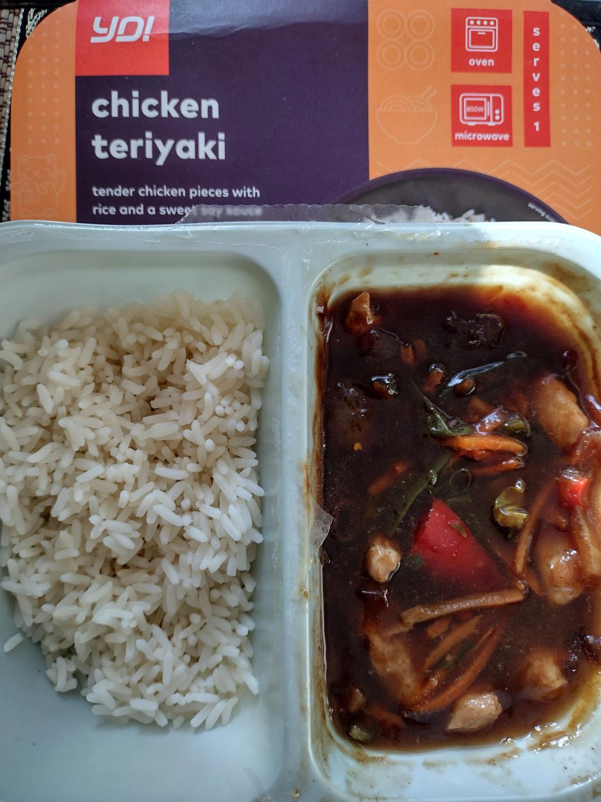 The cooked YO! low-calorie Chicken Teriyaki ready meal with its orange packaging, showing the chicken, vegetables, and rice in the tray.