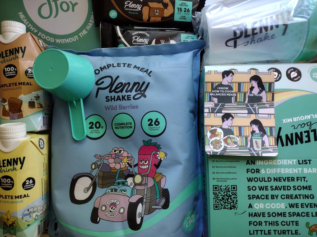 An arrangement of Jimmy Joy complete food products from a taster pack. In the centre is a bag of Plenny Shake in Wild Berries flavour with a teal scoop, surrounded by Plenny Drink cartons and Plenny protein bars.