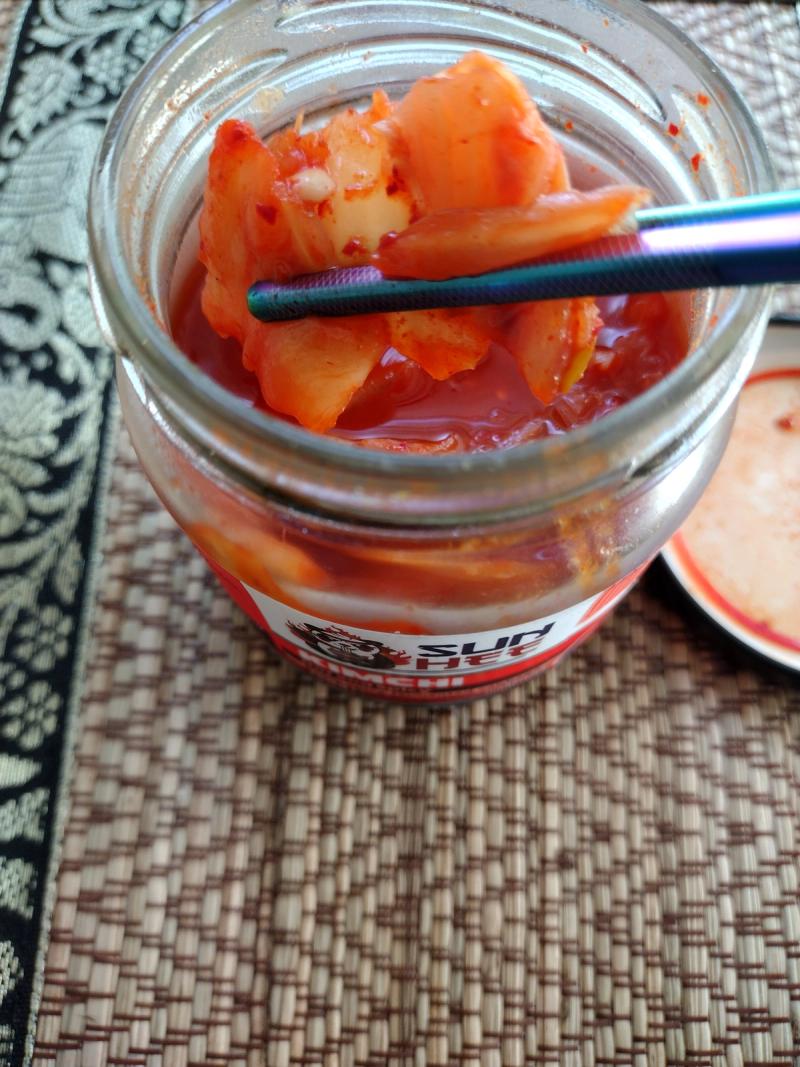 Image of Sun Hee Kimchi (Hot & Spicy 190G) in a glass jar, showing mushy cabbage and watery liquid. This visual evidence supports a critical review of its sweetness and lack of authentic fermentation.
