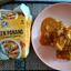 Review image of the Kitchen Joy Thai Cube Chicken Panang ready meal. The finished dish of chicken curry and rice sits on a plate next to the official product packaging, showing the branding and serving suggestion.
