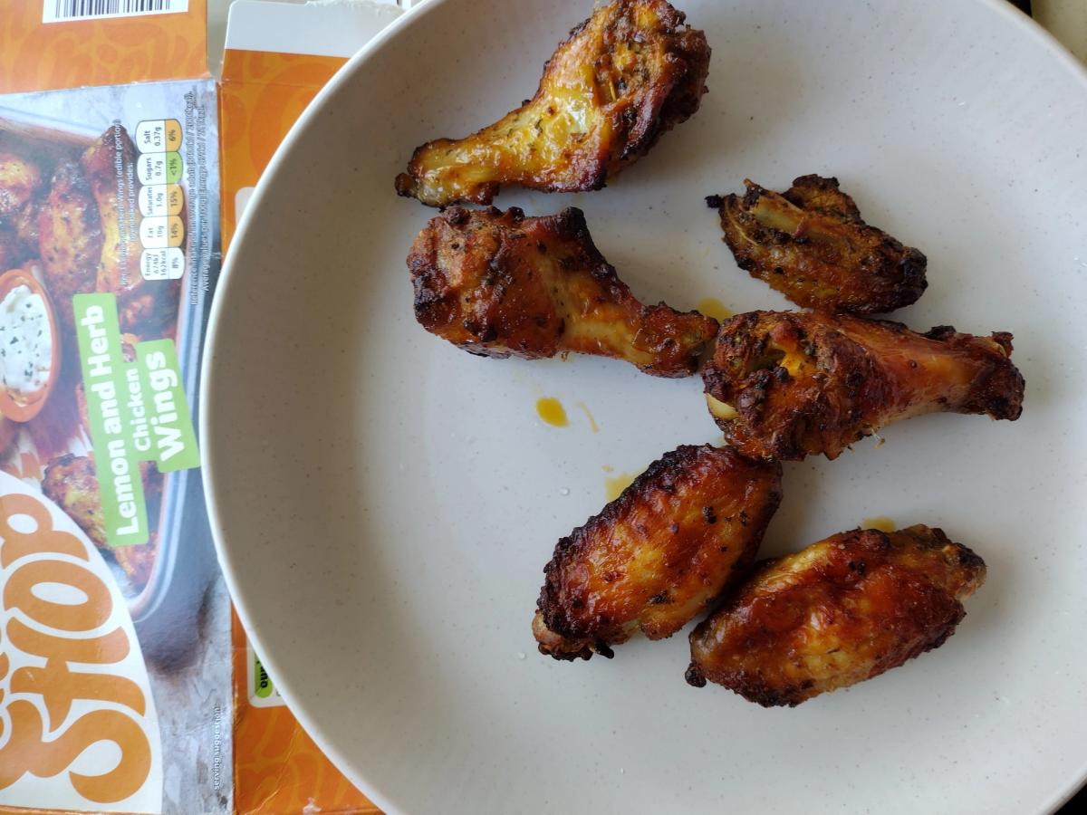 A cooked portion of Birds Eye frozen Lemon and Herb chicken wings showing a dark, sticky caramelised glaze.