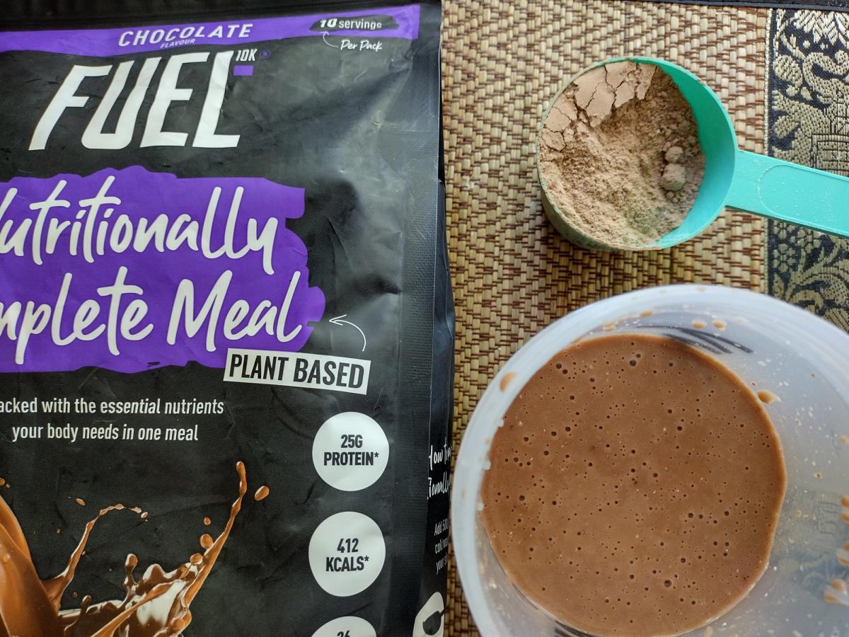 FUEL10K chocolate meal replacement powder and prepared shake, showing the pale colour which contrasts with the product packaging.