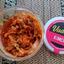 An open tub of Vadasz Kimchi, a popular live cultured and naturally fermented food in the UK. The fresh vegan kimchi is shown next to the pink Vadasz branding on the lid.