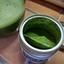 Open tin of Ocha & Co. Single Cultivar Yabukita matcha showing vibrant green colour and fresh powder clumps next to prepared usucha.