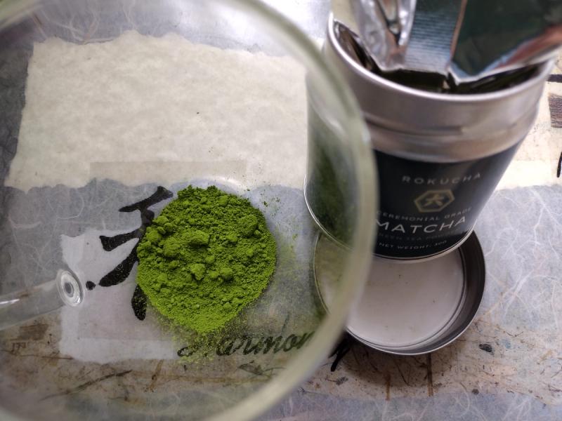 A photo of ROKUCHA's ceremonial matcha's fresh powder, showing high quality alongside the official tin.