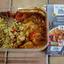 An overhead review photo of the M&S High Protein Tandoori Chicken. The prepared low-carb meal, showing the chicken in sauce and the cauliflower pilau, is in its tray next to the product packaging.