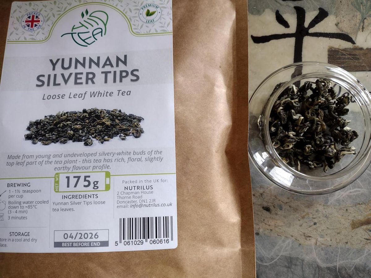 Packaging for Nutrilus Yunnan Silver Tips Loose Leaf White Tea (175g) showing product details, brewing instructions, and a glass bowl containing the dry, silvery-green twisted tea buds and young leaves.