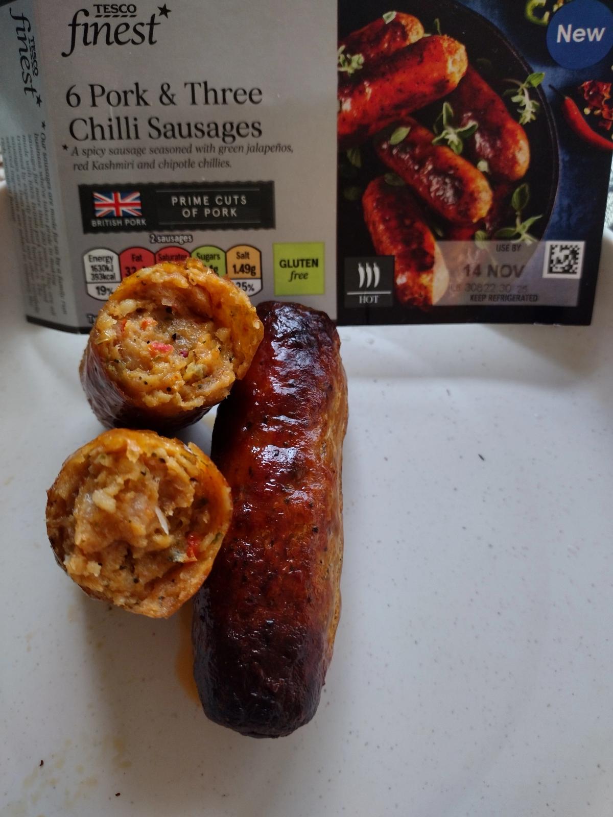 cooked tesco finest pork and three chilli sausages cut open showing bright orange spicy meat texture next to packaging