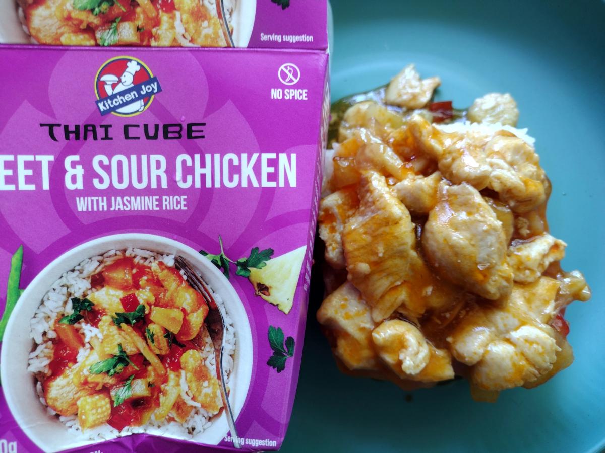 Review image of the Kitchen Joy Sweet & Sour Chicken from their Thai Cube range. The finished dish, featuring chicken in a glossy sauce over rice, is displayed next to the box to illustrate the ready meal's appearance.