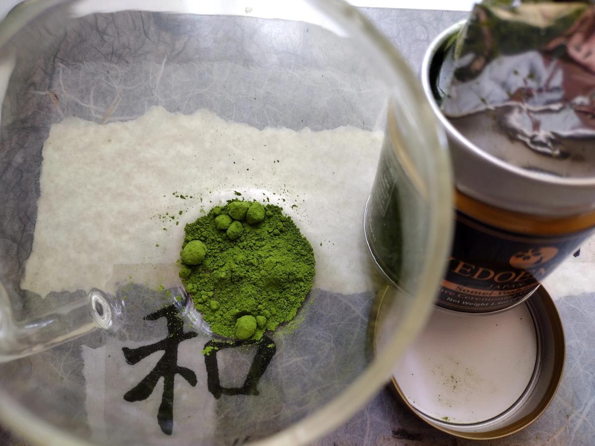 A photo showing the YEDOENSIS pure ceremonial matcha in a clear cup, alongside the tin.