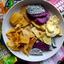 A white bowl filled with an assortment of Soul Fruit brand dried snacks, featuring crunchy purple and white freeze-dried dragon fruit chips, flat soft-dried mango slices, irregular freeze-dried mango chunks, and yellow jackfruit chips. Colorful Soul Fruit packaging bags for Keo Mango and Dragon Fruit surround the bowl.