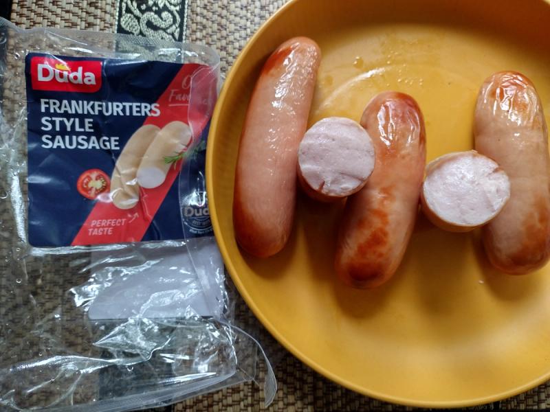 Cooked Duda Frankfurters Style Sausages on a yellow plate, with one sliced to show the cross-section.