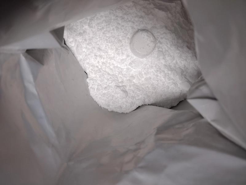 A close-up look inside a 1kg bag of Bulk micronised creatine powder, with the clear scoop visible.