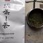 Overhead shot of Ocha & Co. Fukamushicha packaging with Japanese characters for 'Fukamushicha' (深蒸し茶). To the right, an open container reveals the fine, deep green loose leaf tea. The background is a textured, artistic surface."