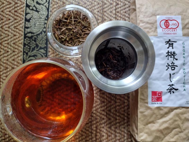 Ocha & Co. organic Japanese hojicha, showing the loose-leaf roasted green tea, a brewed amber cup, and the branded packaging.