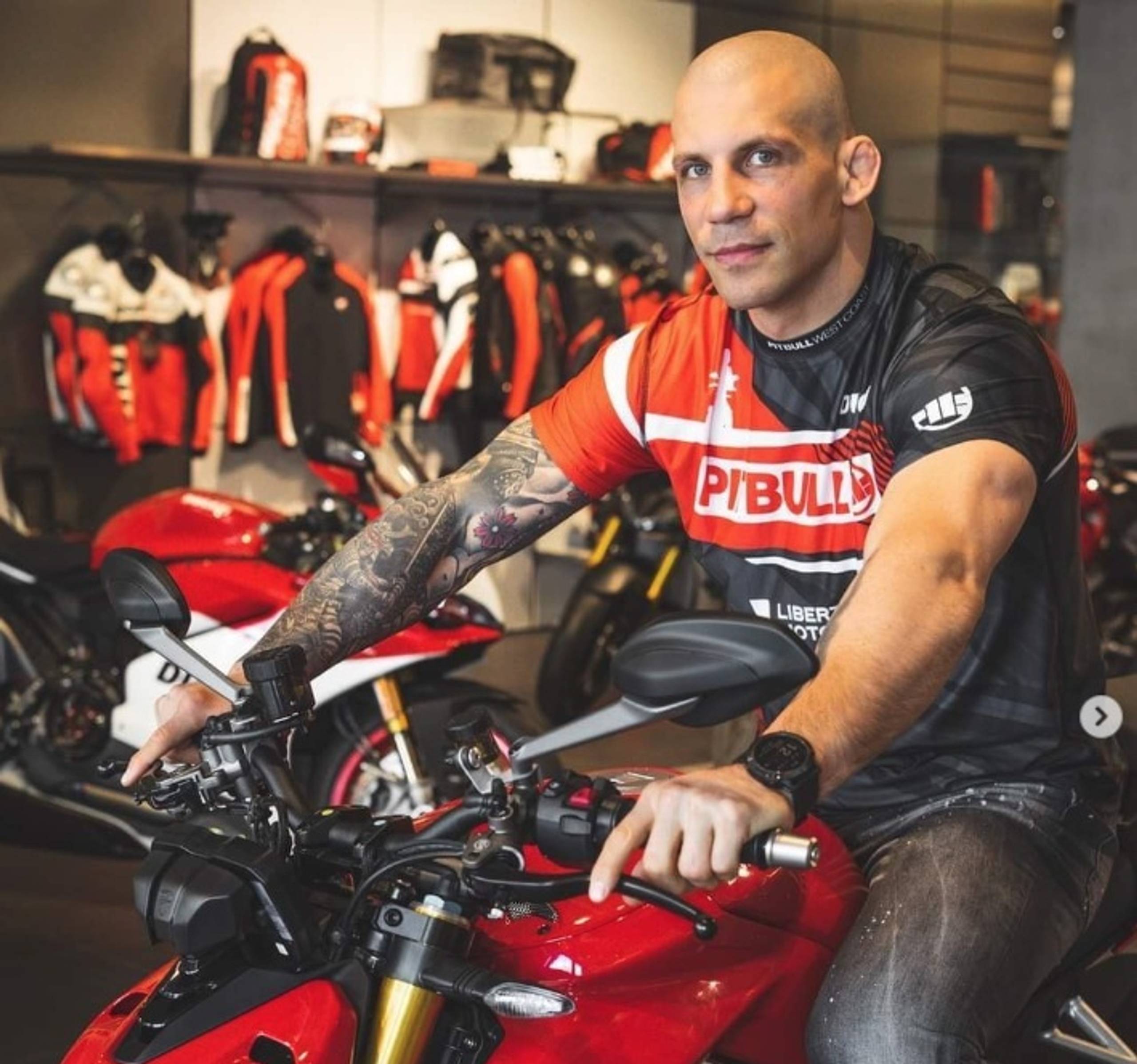 Mężczyzna w koszulce Pitbull na czerwonym motocyklu sportowym