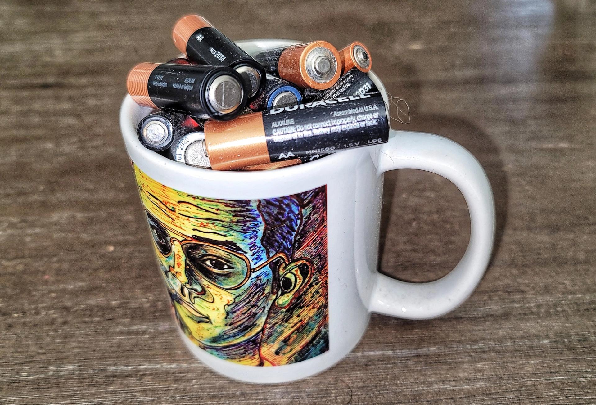 Photo of a coffee cup filled with old batteries.
