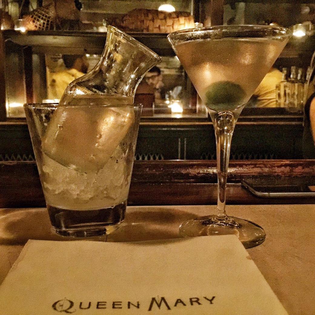 Sidecar on ice and a martini sitting on bar with branded napkin in front of them