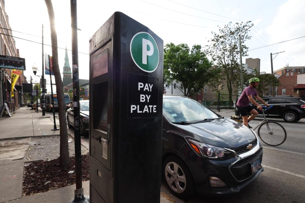 A parking meter on a sidewalk of a street with cars and bikes