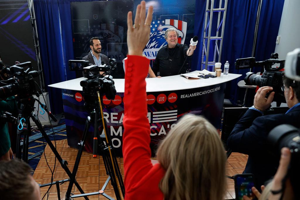 A political podcast recording takes place with hands raised
