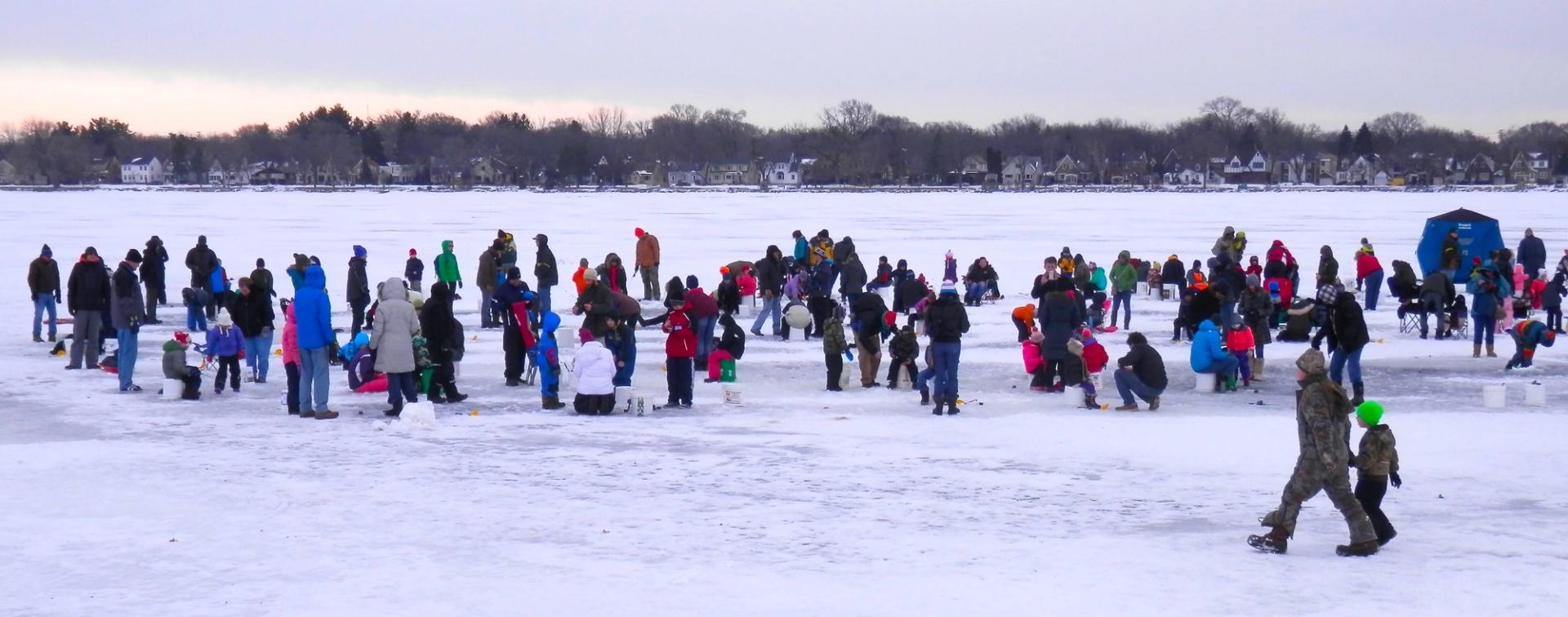 A group of people in winter gear standing on a frozen lake.