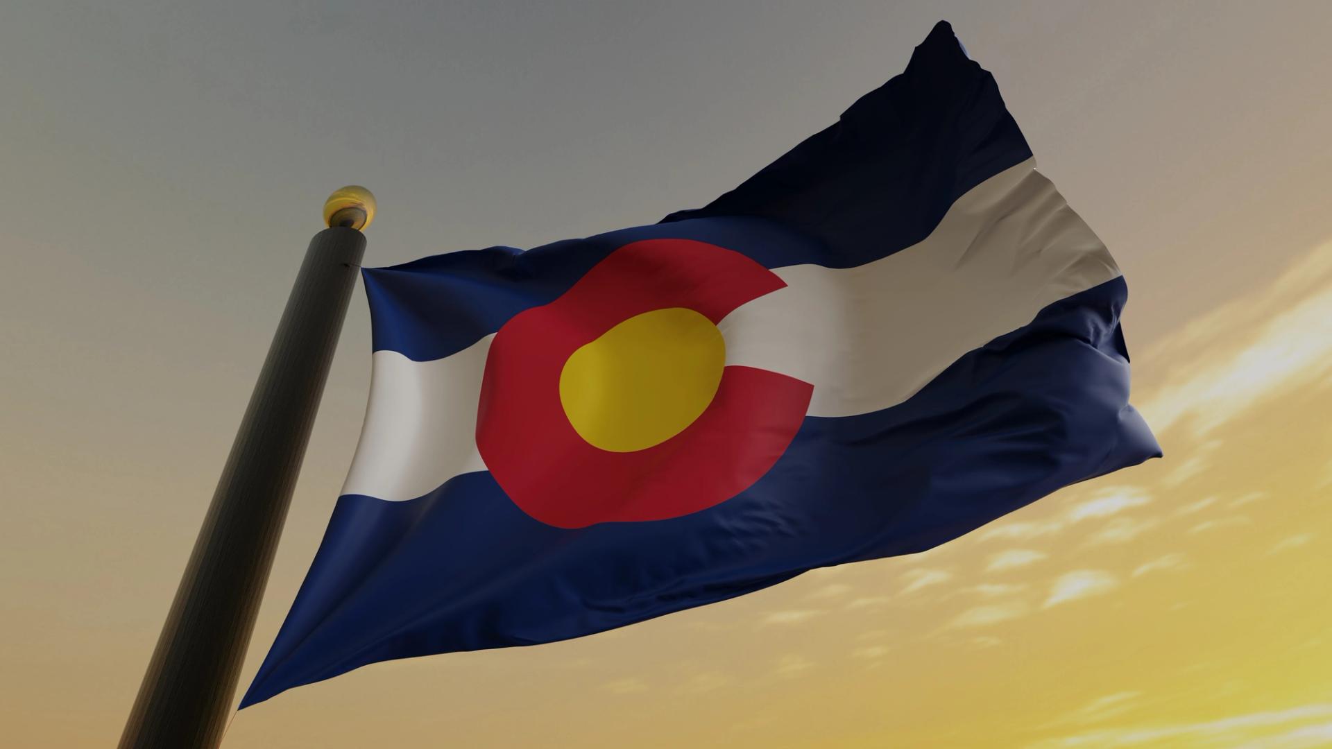 The Colorado flag blows in the wind against a dusk-y sky