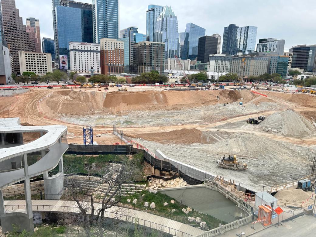 A construction pit filled with dirt against Austin's skyline.