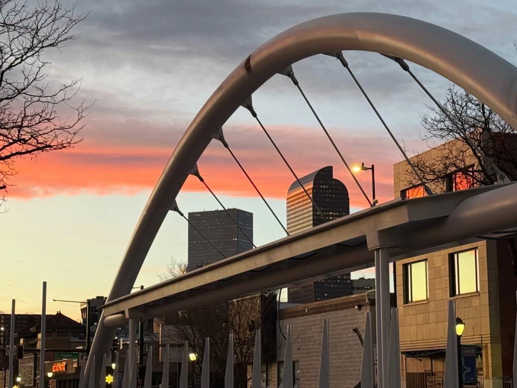 A metal arch over a bus stop stands against the sunset. 