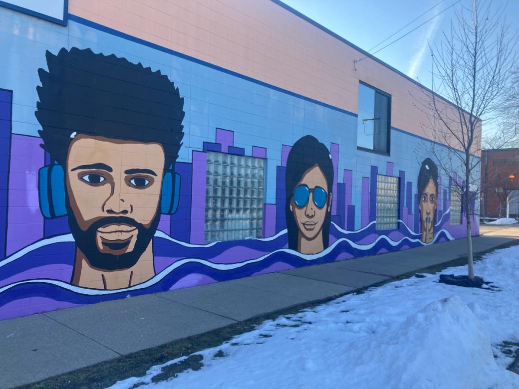 A long purple mural with three faces on it.
