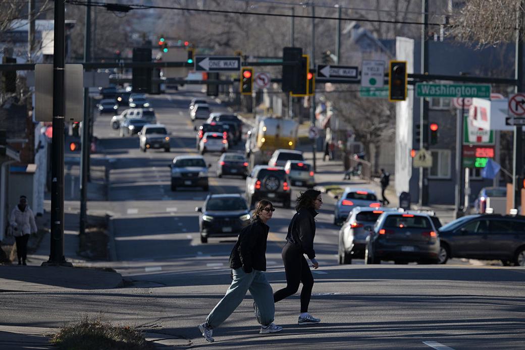 People cross a busy street while looking out for cars