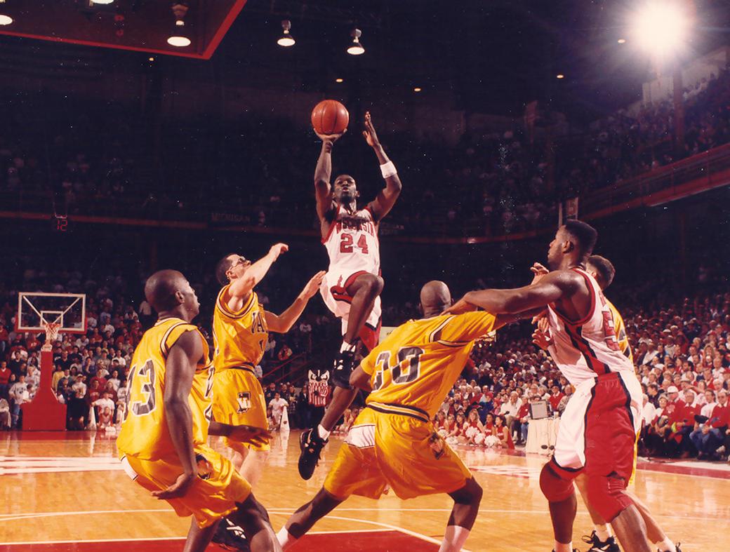 Finley is pictured jumping over multiple opposing players to dunk a basketball. photo taken at a game in the 1990s