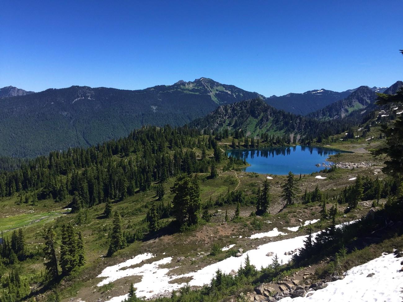 lake with mountains in the background and snow in foreground