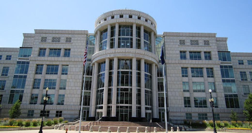 A photo of a courthouse with the words “Scott M. Matheson Courthouse” on the front, featuring two flag poles and two lamposts in Salt Lake City, Utah.