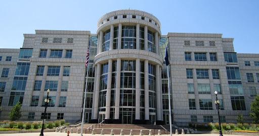 A photo of a courthouse with the words “Scott M. Matheson Courthouse” on the front, featuring two flag poles and two lamposts in Salt Lake City, Utah.