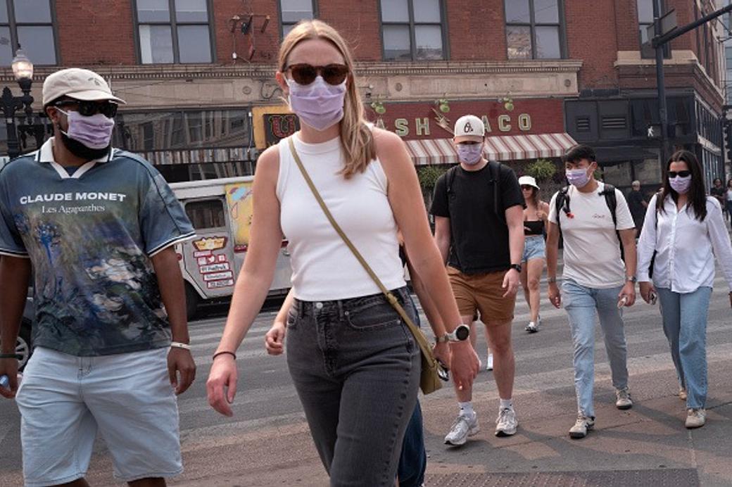 A group of people walking on a street with purple masks and sunglasses on