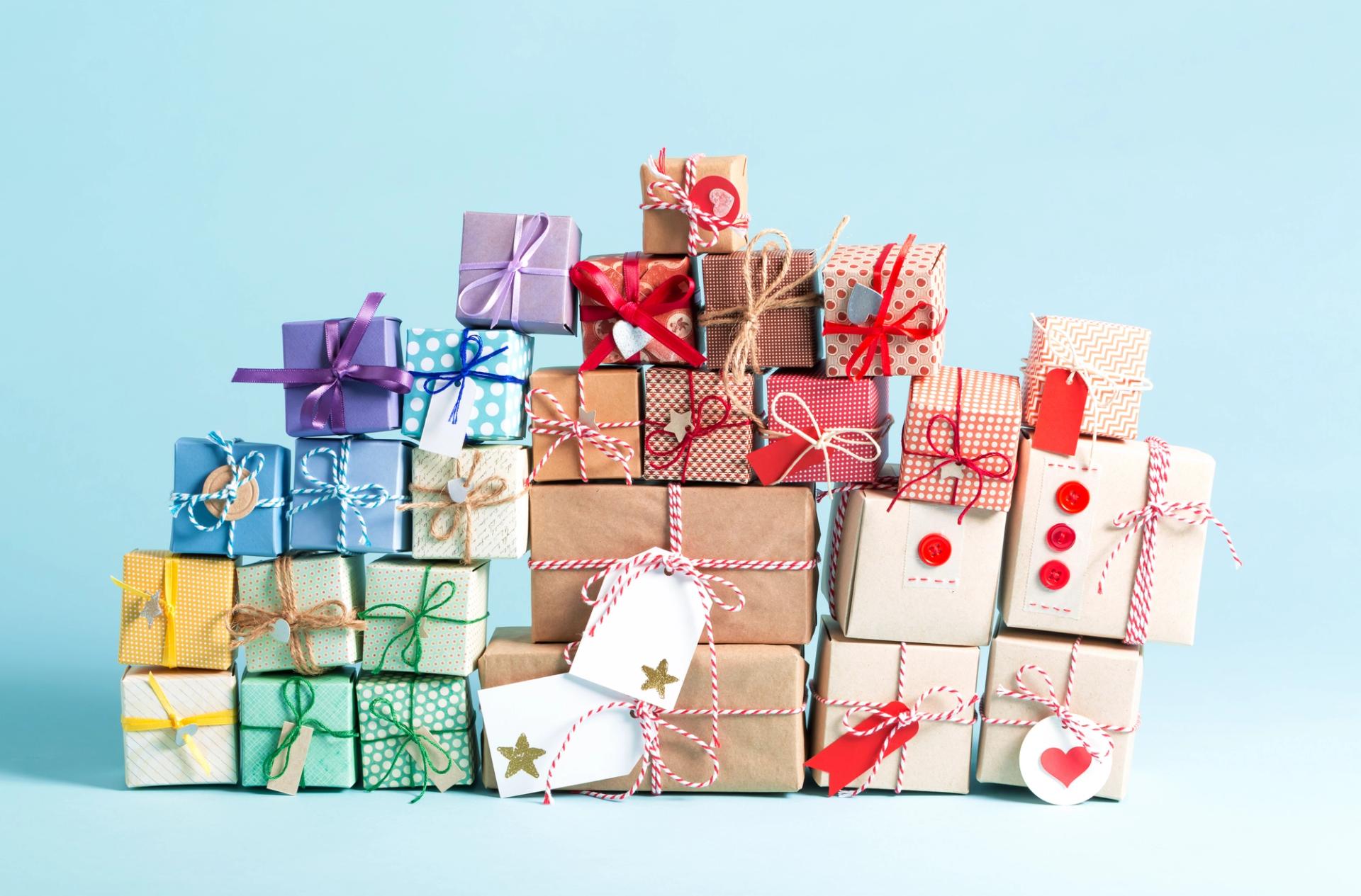 A bunch of colorfully wrapped gifts against a light blue background.