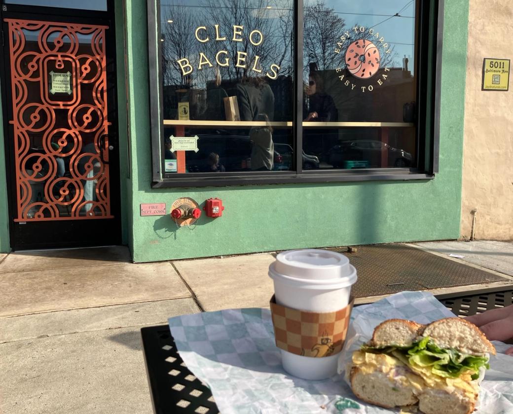 Exterior of Cleo Bagels with a coffee cup and bagel in the foreground