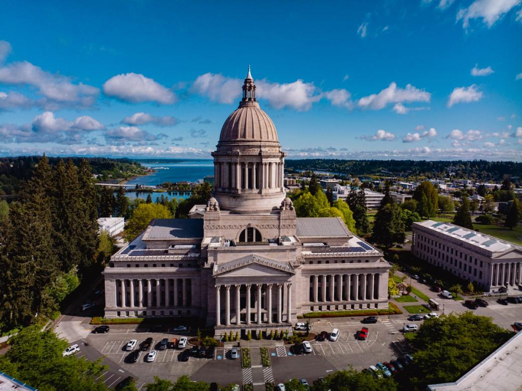 An image of the capitol building in Olympia with the trees and water behind