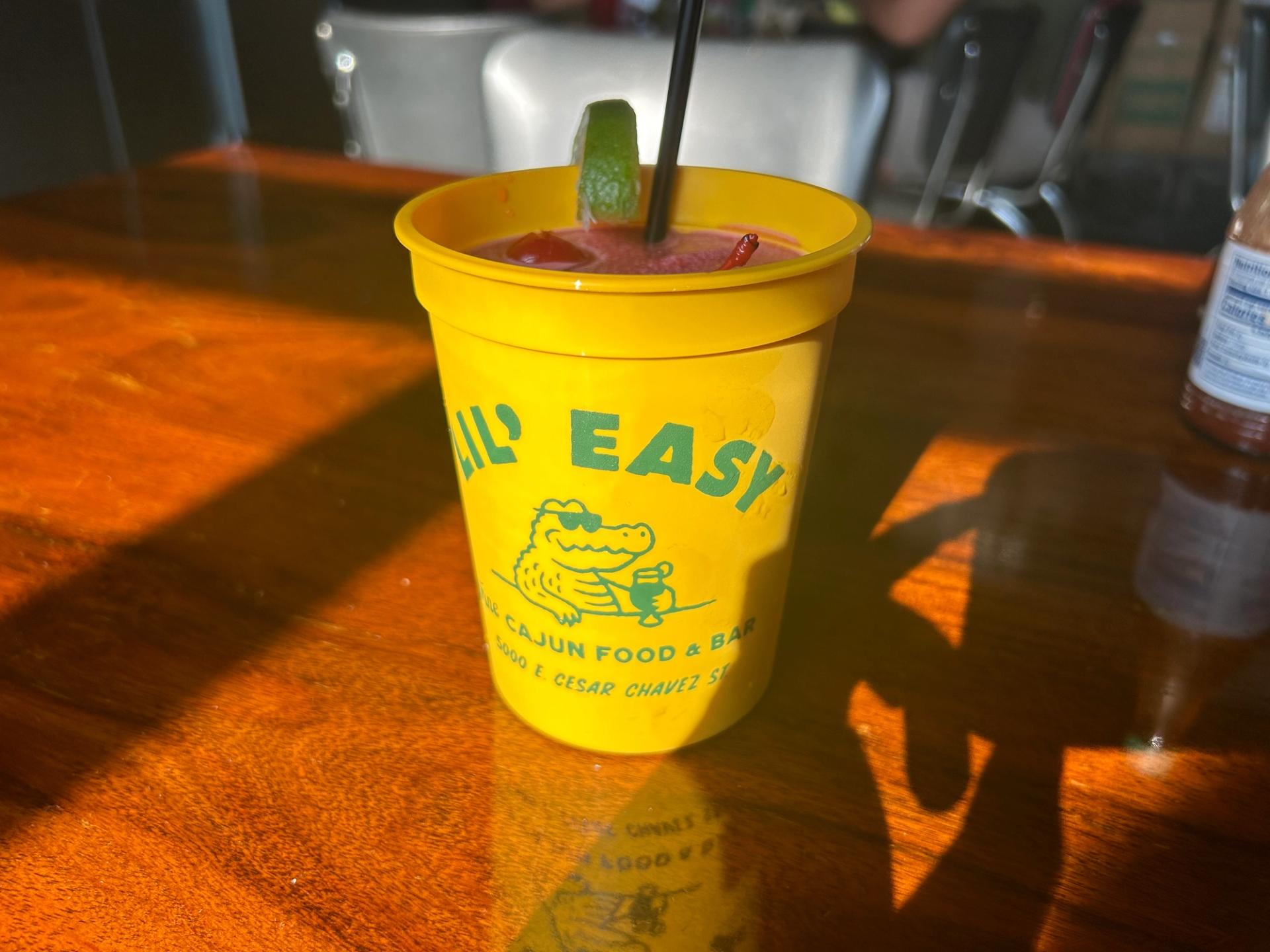 A yellow, plastic cup with a hunter green alligator wearing sunglasses on it.
