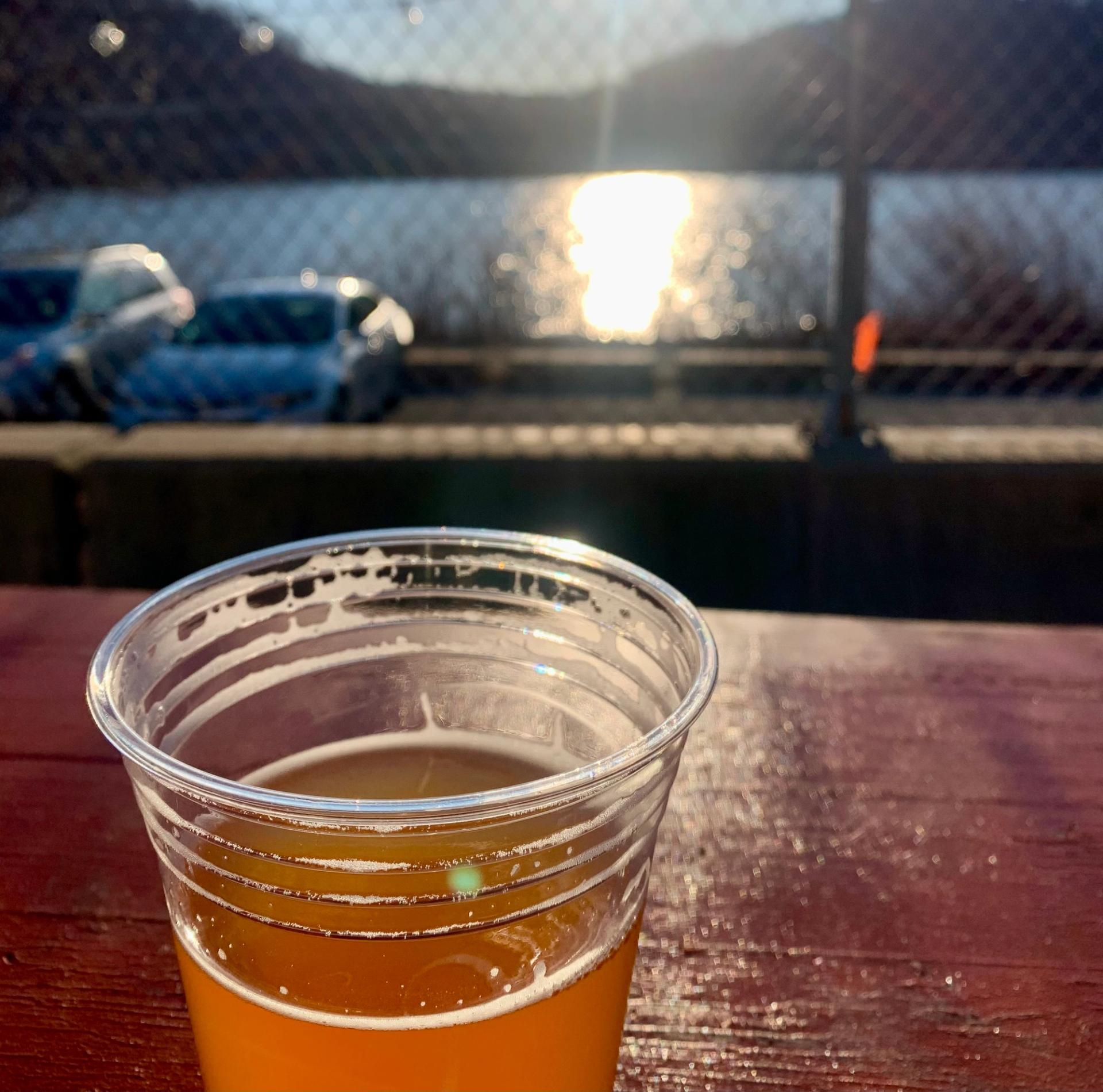 a beer in the foreground with a sunlit river behind