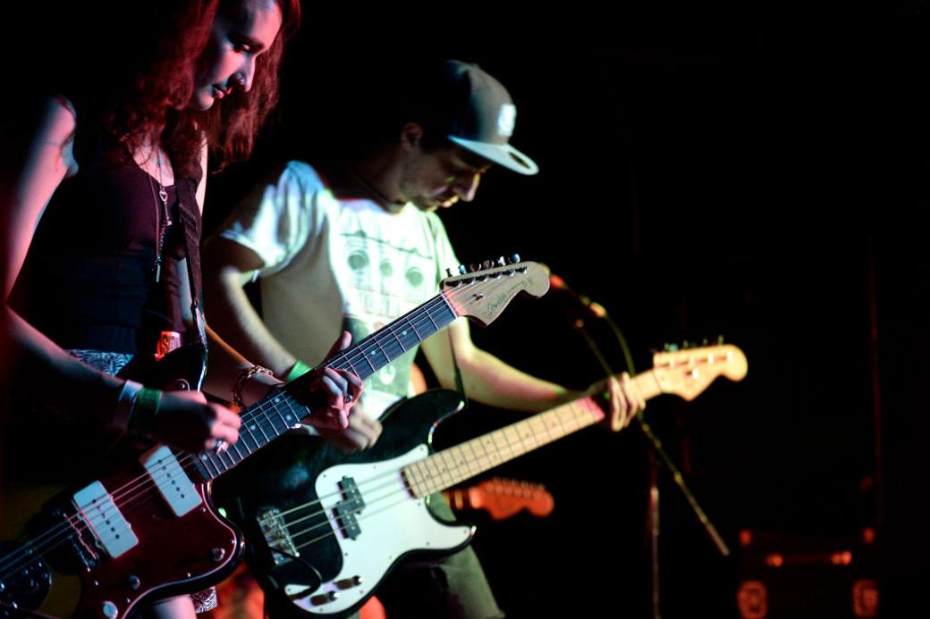 Two people with guitars in a band play on stage
