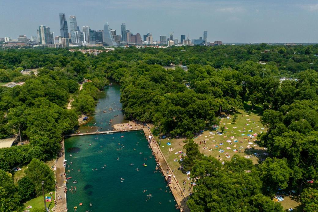 An aerial shot of Barton Springs Pool with Austin's skyline in the background.