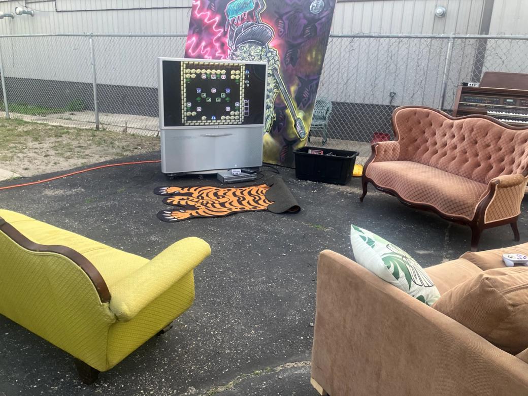 A TV in a parking lot with three couches.