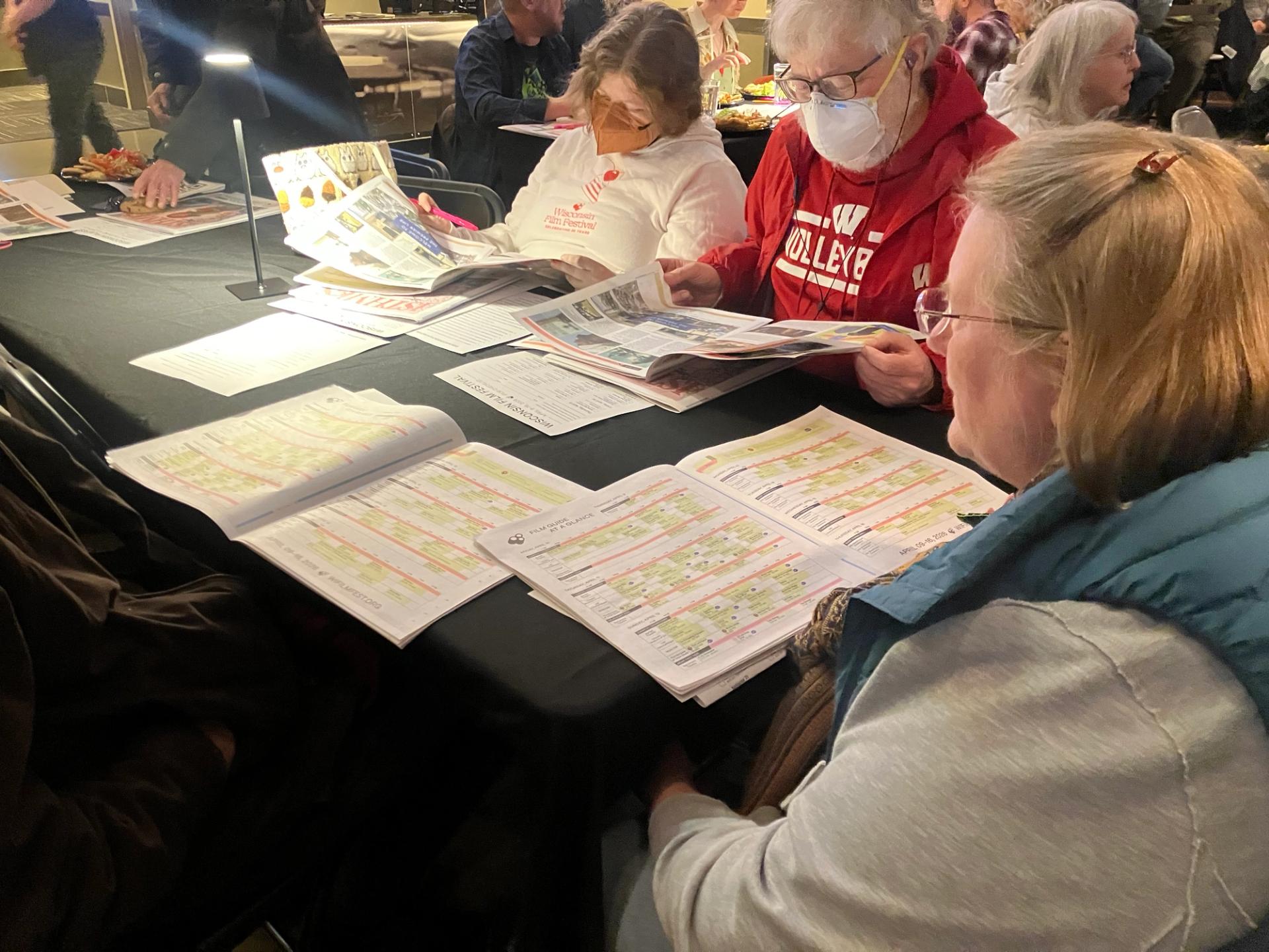 Two women look over a schedule on a table.