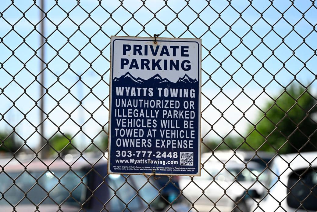Parking sign on a fence warns of towing in Denver