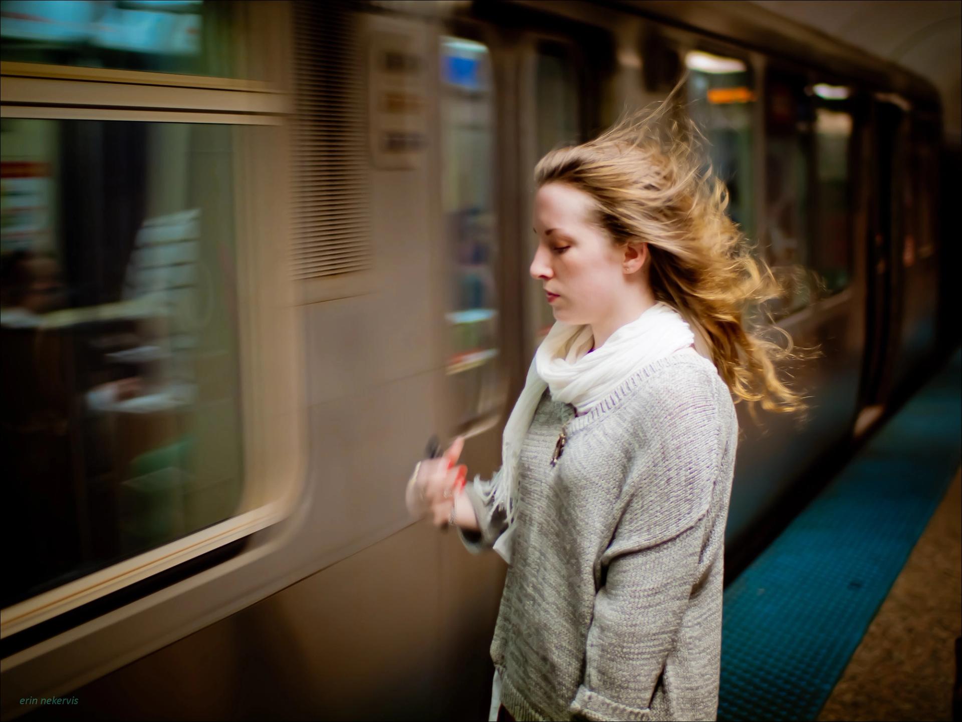 A girl is hit by the gust of an approaching Red Line train.