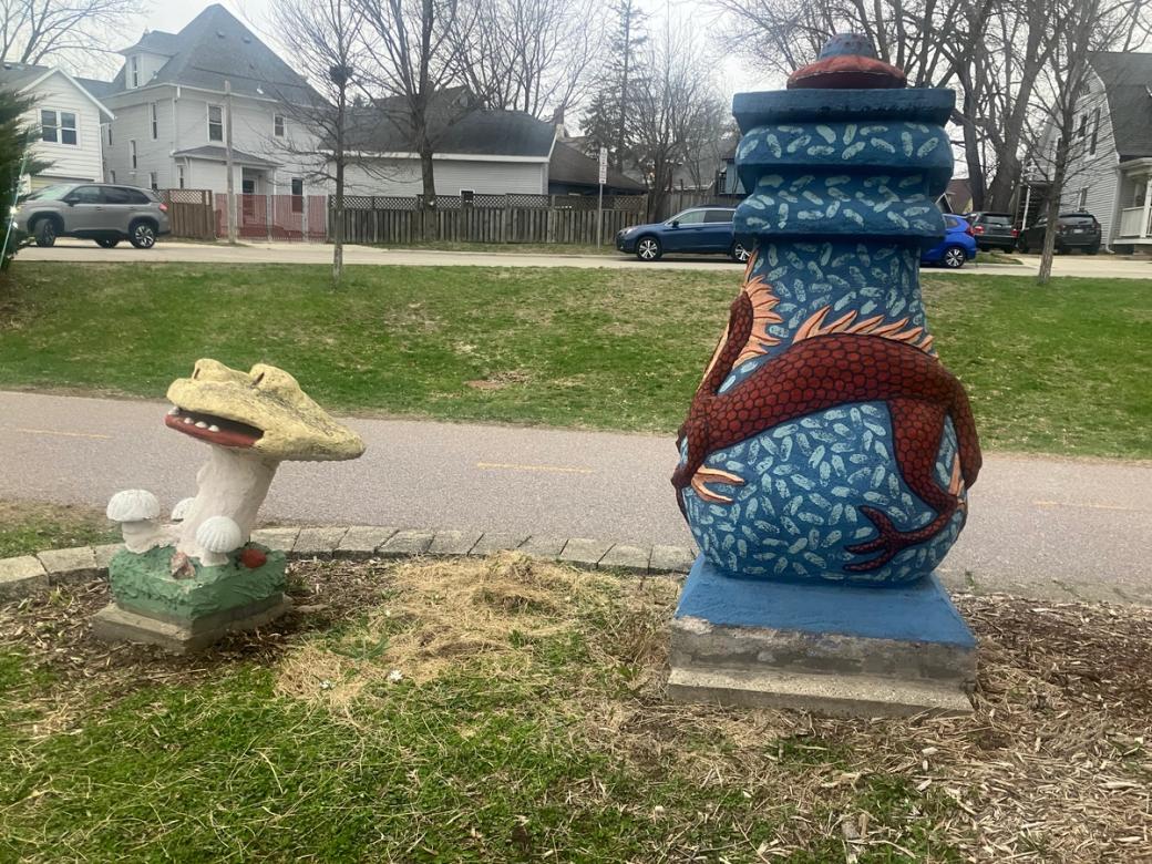 A statue of a blue urn and of a mushroom by the side of a path.